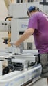 Mitarbeiter in einer Schreinerwerkstatt bedient eine präzise Holzbearbeitungsmaschine.