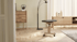 Ergonomischer, rückenfreier Stuhl mit grauem Sitz und Holzgestell auf Rollen in einem Wohnzimmer.
