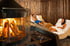 Mann und Frau entspannen auf Liegen am Kamin in einem Spa-Ruheraum mit Holzpaneelen.