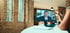 Eine Person führt ein Videotelefonat an einem Monitor in einem Büro mit Backsteinwänden.