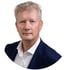 Ein Mann mit blonden Haaren im Anzug blickt nach vorne.