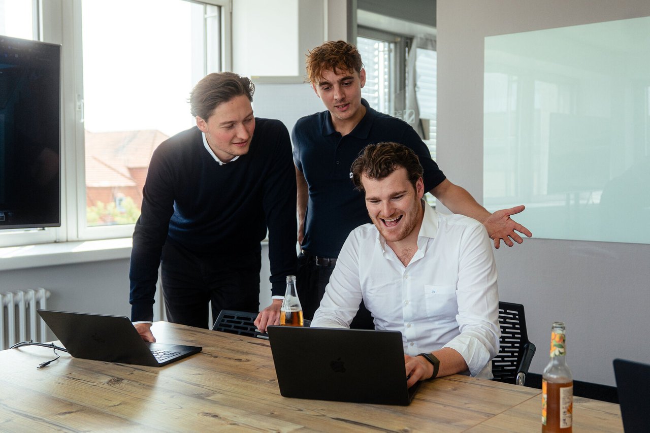 Drei Kollegen schauen gemeinsam auf einen Laptop