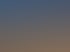 Ein hölzerner Dachstuhl im Rohbau mit parallelen Sparren vor einem klaren, blauen Himmel.
