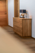 Heller Raum mit Holzboden und einer Holzkommode mit Lampe und Stierfigur.