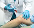 PRP Treatment: Doctor in blue gloves injecting a syringe with red liquid into a patient's knee.