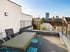 Dachterrasse mit Esstisch, Stühlen und Stadtblick bei sonnigem Wetter.