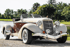 Beiges und braunes Auburn Speedster Oldtimer-Cabriolet mit weißen Reifen, geparkt neben einem See.