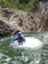 Ein Mann in einem blauen Helm und Neoprenanzug steht im sprudelnden Wasser eines Gebirgsflusses.
