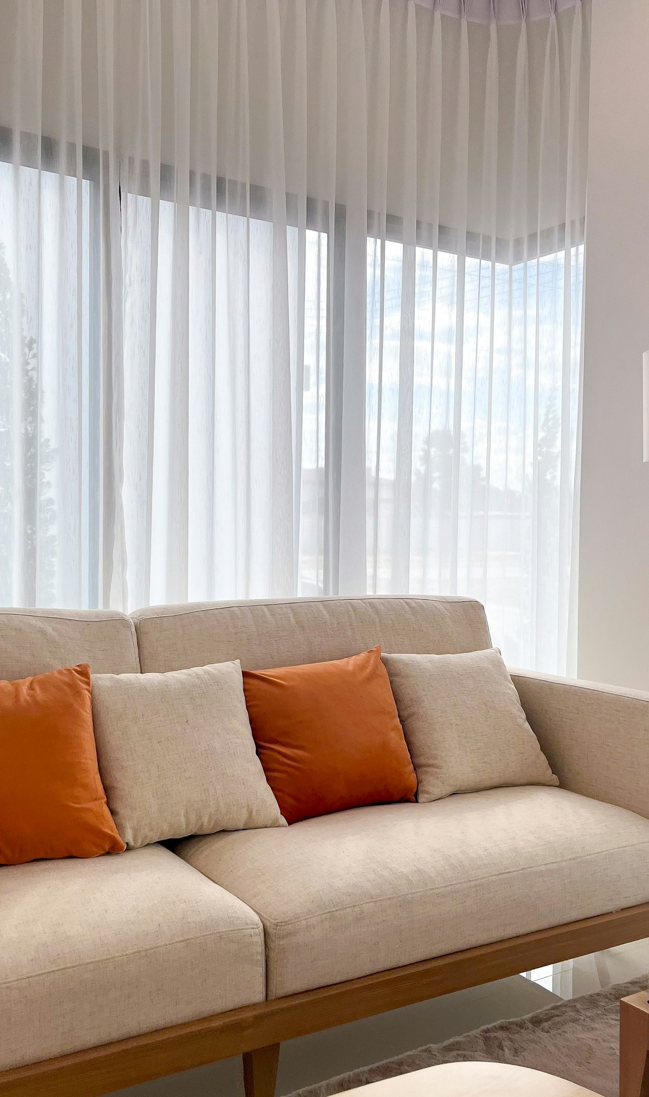 Weiße transparente Vorhänge vor einem Sofa im Wohnzimmer