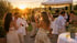 Gäste tanzen und feiern bei einer sommerlichen Gartenparty im Sonnenuntergang mit DJ unter einem weißen Pavillon.