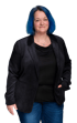 Eine lächelnde Frau mit blauen Haaren, schwarzem Blazer und Jeans, die Hände in den Taschen.
