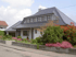 Modernes Haus mit dunkelgrauem Ziegeldach, weißen Wänden und gepflegtem Vorgarten mit bunten Blumen.