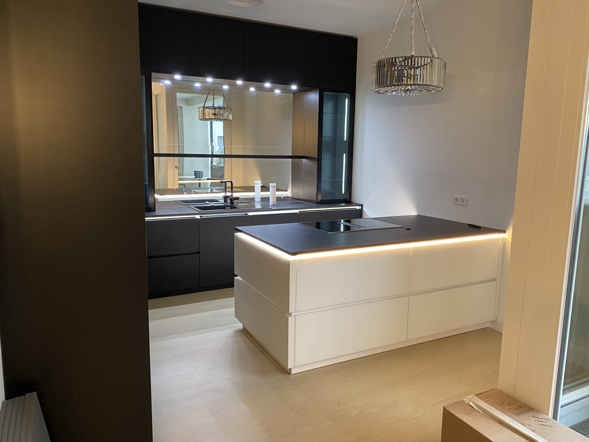 Schwarz-weiße Designküche mit beleuchteter Kochinsel und Spiegelrückwand