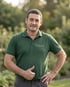 Pawel R., Vorarbeiter bei Volker Möller GalaBau, im grünen Firmenpolo im Garten.