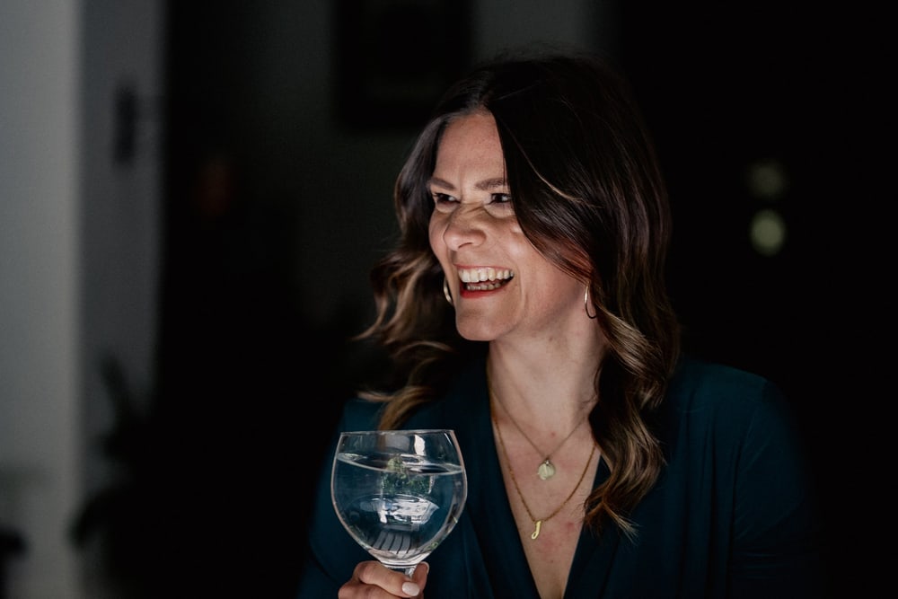 Frau lacht mit Glas in der Hand