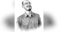Black and white portrait of a smiling man with a beard and glasses, looking up and to the right.