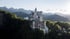 Schloss Neuschwanstein auf einem bewaldeten Hügel, umgeben von Bergen, mit einem See im Hintergrund.