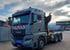 Grauer MAN LKW mit Ladekran und rot-weiß gestreifter Warnmarkierung auf einem Betriebshof.