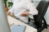 Person sits at a desk, holding their aching lower back with one hand.