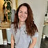 Lächelnde Frau mit langen braunen Haaren in einem grauen Poloshirt mit dem Logo "Vinessa für Frauen".