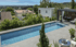 Langer, schmaler Pool mit blauen Fliesen und umliegender Terrasse mit Pavillon und Sitzgelegenheiten.