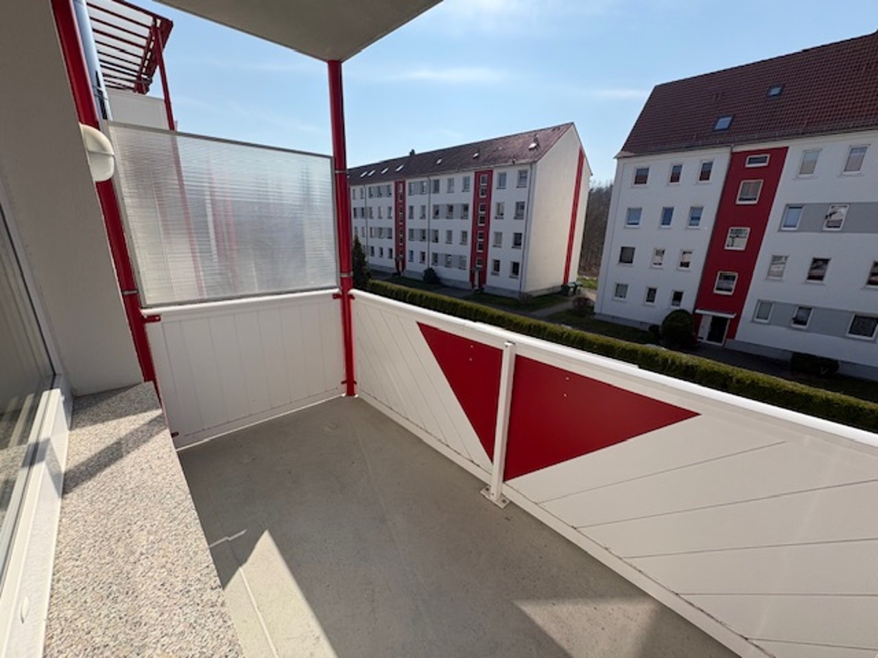 Balkon mit rot-weißem Geländer und Blick auf die Nachbarhäuser