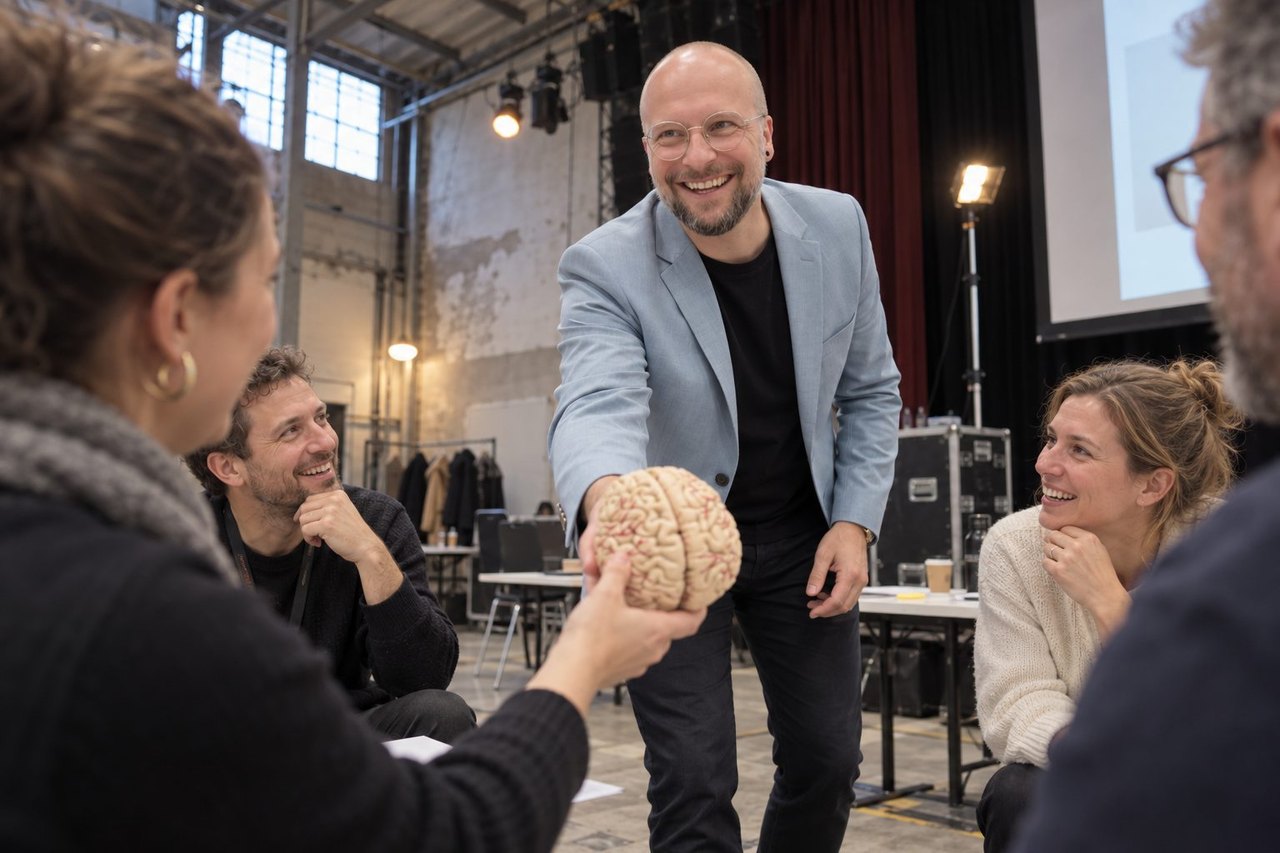 Trainer reicht einer Gruppe in einer Werkhalle ein Gehirnmodell