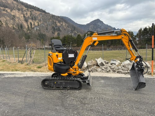 Minibagger von MK-Baggerungen vor Bergkulisse