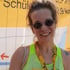 Lächelnde Frau mit runder Sonnenbrille, neon-gelbem Sport-Top und Medaille vor einer gelben Karte.