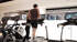 Ein Mann und eine Frau trainieren auf Laufbändern in einem modernen Fitnessstudio mit Monitoren.