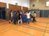 Schüler schieben eine blaue Matte auf Rollen in einer Sporthalle.