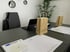 Konferenzraum mit Laptop, zwei Papiertüten, Stuhl, Stift und Dokumenten auf einem dunklen Tisch.
