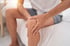A man holding his knee in pain, with a focus on the joint.