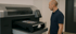 Mann bedient einen schwarzen T-Shirt-Drucker mit einem bedruckten T-Shirt darauf.