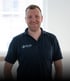 Matthias Hemminger im dunkelblauen Poloshirt mit dem Logo von Faller Sicherheitstechnik GmbH vor hellem Hintergrund.