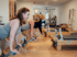 Drei Frauen trainieren in einem Pilates-Studio an Reformer-Geräten und stützen sich mit den Händen auf die Fußstangen.