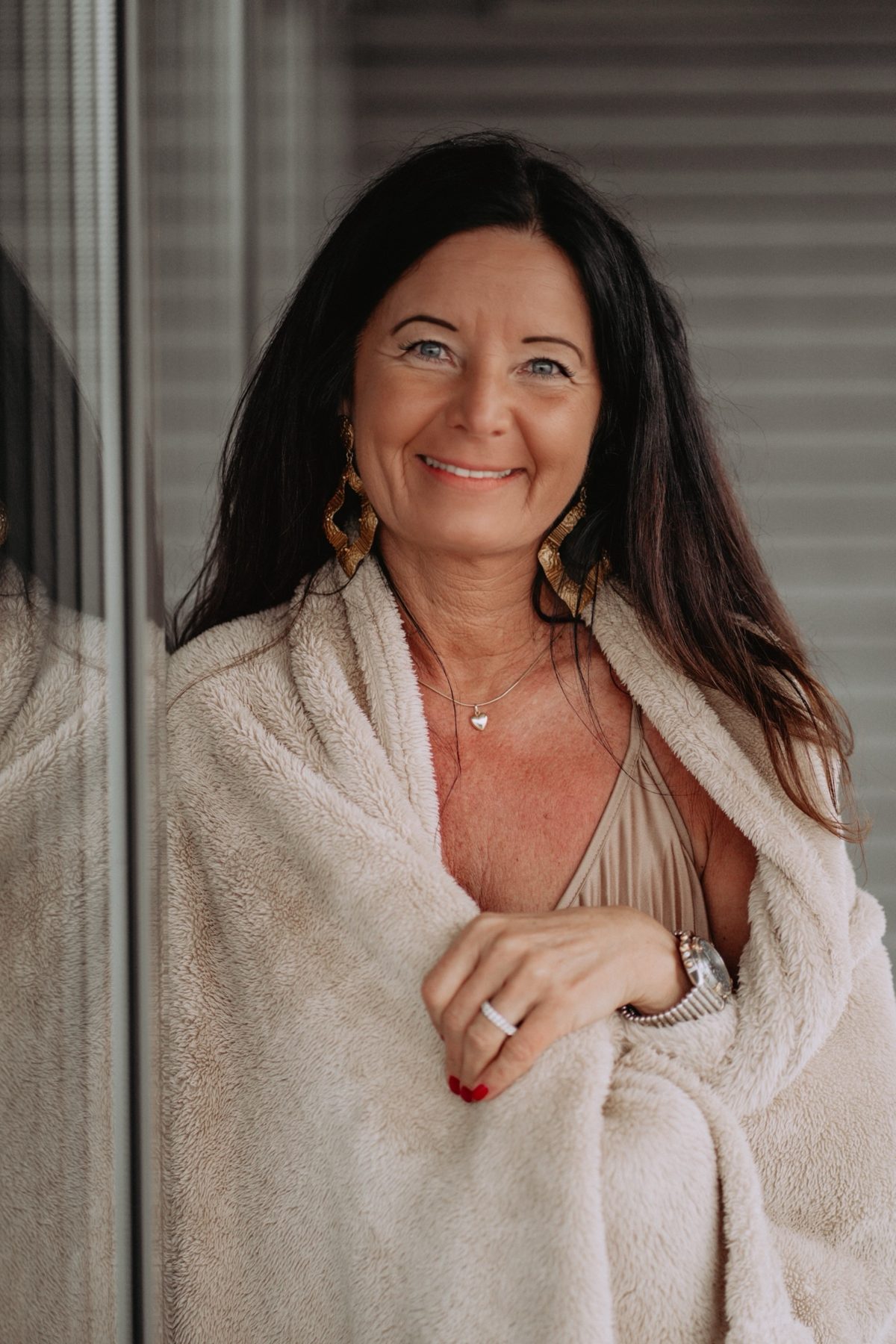 Manuela Reudink, lächelnd, in eine helle Decke gehüllt