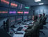 Drei Männer in Uniform mit Headsets sitzen vor Computern mit vielen Monitoren, die Wellenformen und Daten anzeigen.