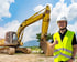 Ein lächelnder Bauarbeiter in Warnweste und Helm gibt vor einem gelben Bagger den Daumen hoch.