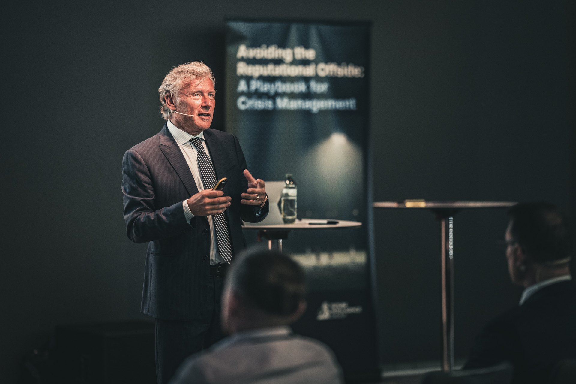Keynote auf der Bühne vor einem Roll-up zum Thema Krisenmanagement