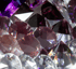 Glänzende, facettierte Diamanten in verschiedenen Größen, mit lila und roten Reflexionen.