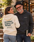 Paar vor einem Bücherladen, die Frau trägt einen cremefarbenen Wearmorrow® Hoodie mit der Rückenbotschaft Verstehen beginnt mit Neugier
