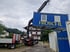Kran hebt blauen Container mit gelbem "FRÖSCHL" Schriftzug von LKW.