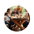 Eine mehrgenerative Familie sitzt gemeinsam an einem rustikalen Holztisch im Freien und genießt eine Mahlzeit.