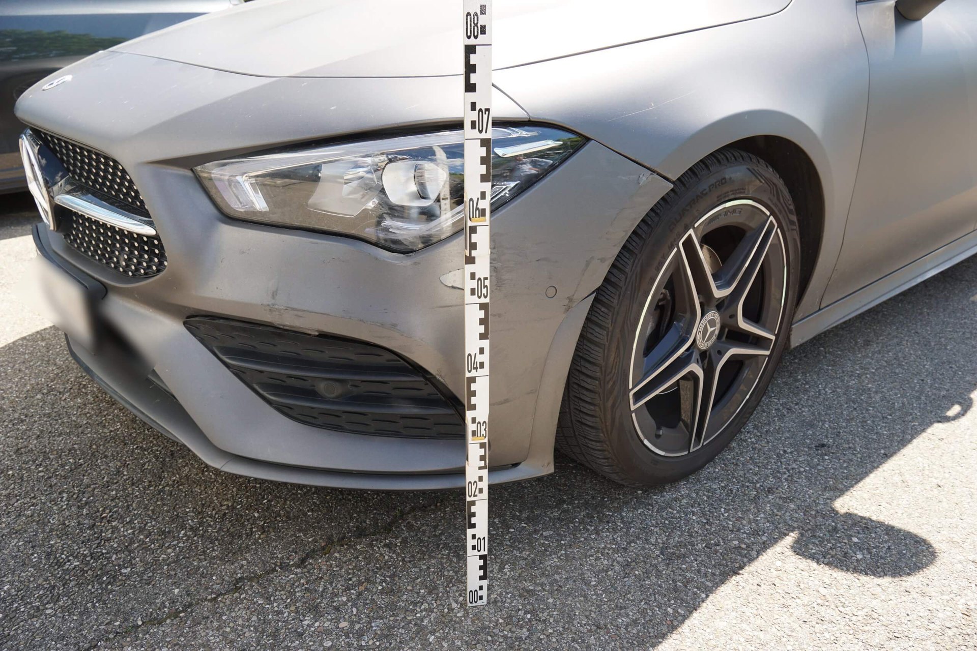 Frontschaden an einem Mercedes CLA mit Sonderfolierung in Grau matt, mit Messlatte bei der Begutachtung durch den Kfz Gutachter in Dischingen