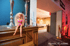 Eine blonde Barbie-Puppe in pinkem Bikini sitzt auf einem Holzmöbel vor zwei Kerzenständern.
