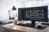 CAD-Software mit Bauplänen auf einem Computermonitor auf einem Schreibtisch mit gerollten Bauzeichnungen.