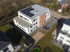 Modernes Mehrfamilienhaus mit Solarpaneelen auf dem Dach und orangefarbener Akzentfassade.