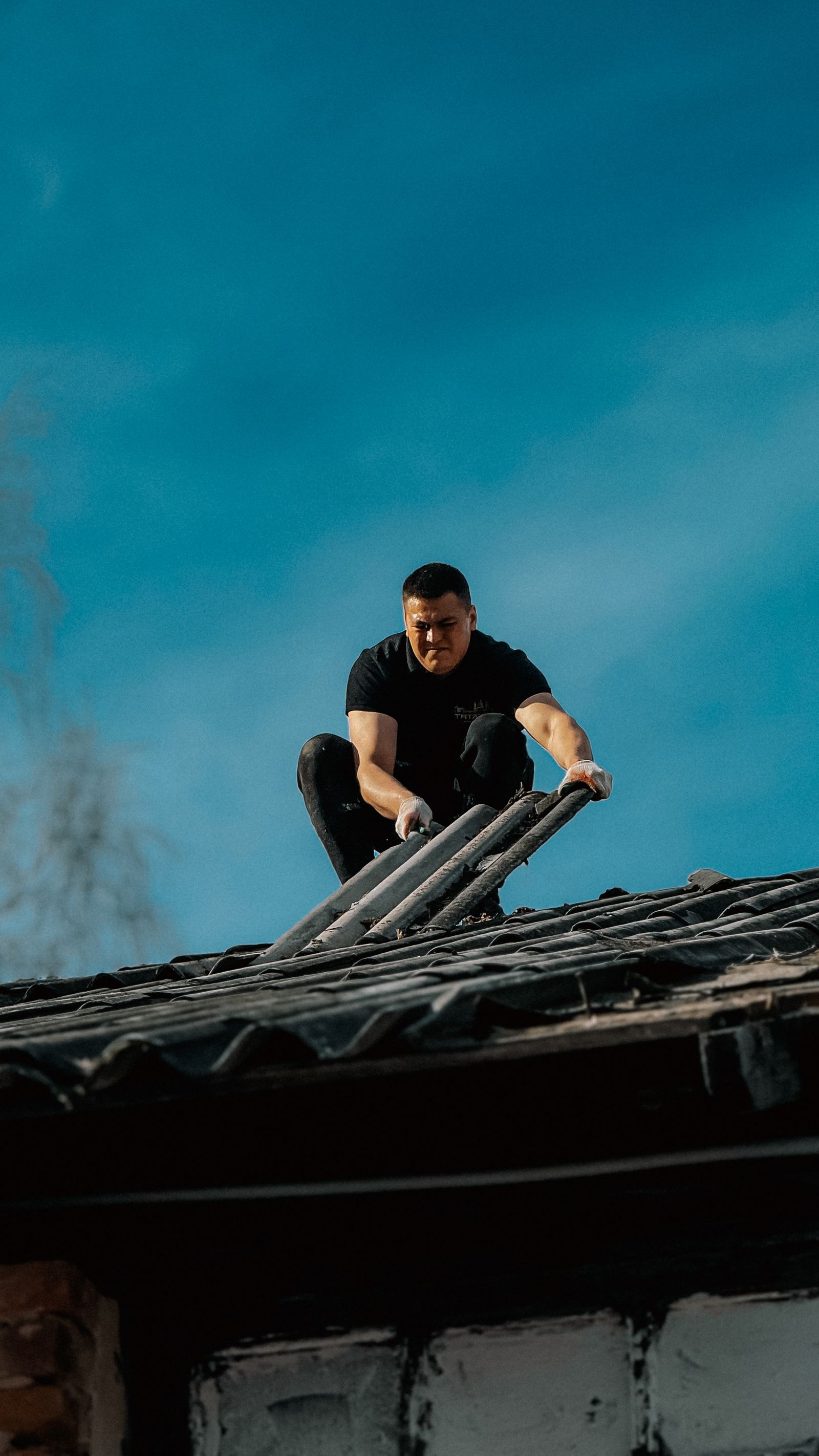Roofer climbing a ladder onto a residential roof to begin an inspection