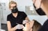 Zahnärztin mit Lupenbrille und Mundschutz untersucht eine Patientin mit zahnmedizinischen Instrumenten in einer Praxis.